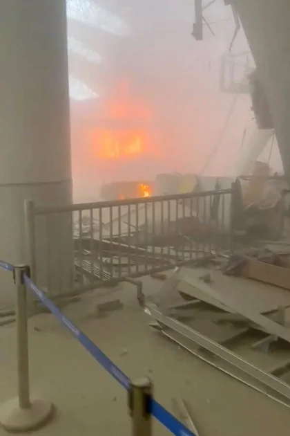 Debris lies on the floor as fire burns in the background in the aftermath of Iranian strikes at Kuwait International Airport on Wednesday.