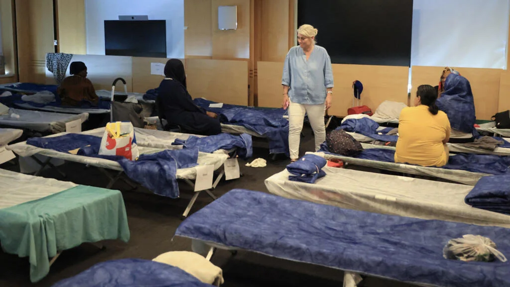 France's Health Minister Stephanie Rist walks amid camp bed as she visits an emergency shelter during the heatwave in Paris on June 26, 2026