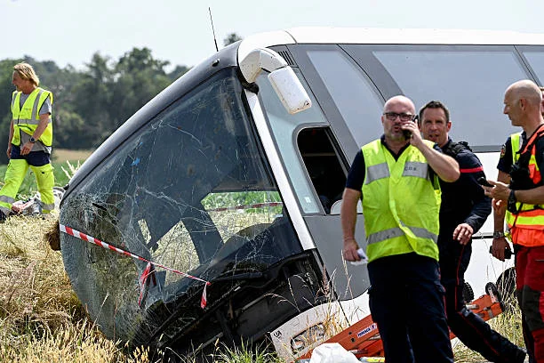 Rescuers and firefighters operate near the damaged bus on the site of the fatal accident on the A81 motorway in Degre, northwestern France, on June...
