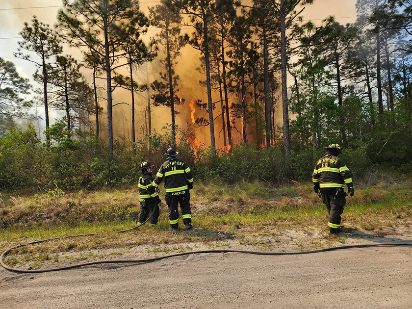 A Southport Fire Department crew is shown working at the 1,500-acre wildfire in Brunswick County in this image Boiling Spring Lakes Fire Rescue posted Friday on social media.