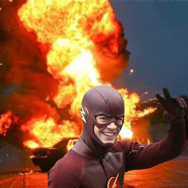 a man dressed as the flash in front of a large fire with his hand up