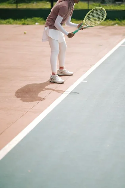 Free Female tennis player prepares to serve on an outdoor court, dressed in sportswear. Stock Photo