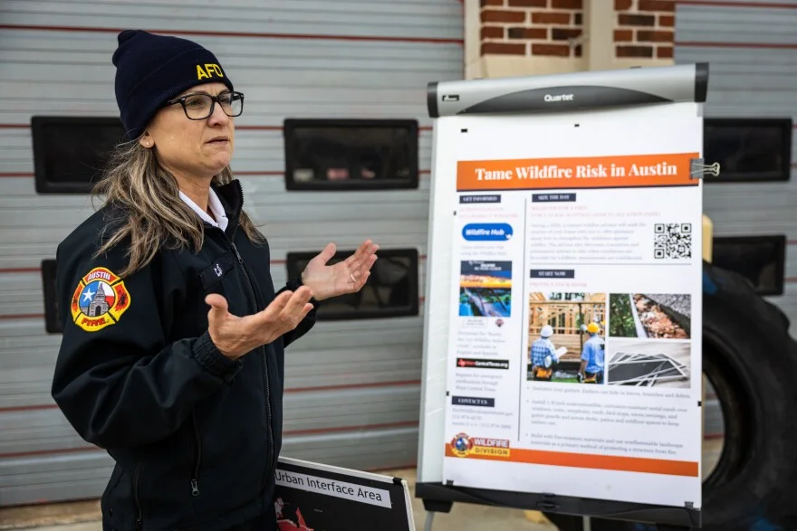 A woman stands in front of a poster explaining local wildfire risk.