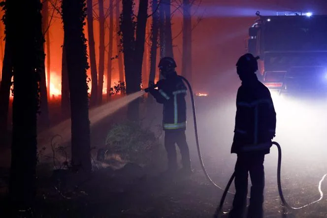 Des pompiers combattent les flammes, dans l’incendie près de Luglon, dans la forêt des Landes, dans la nuit du 13 au 14 août 2026.